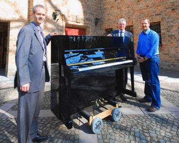 Klaus Kreutzer vom Piano Centrum und Norbert Wendt übergeben Markus Langer ein neues Klavier